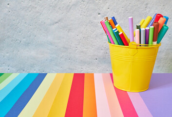Yellow glass filled with colored pencils. Copy space on a colorful table