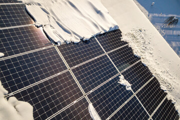 Close up surface of a house roof covered with solar panels in winter with snow on top. Energy...