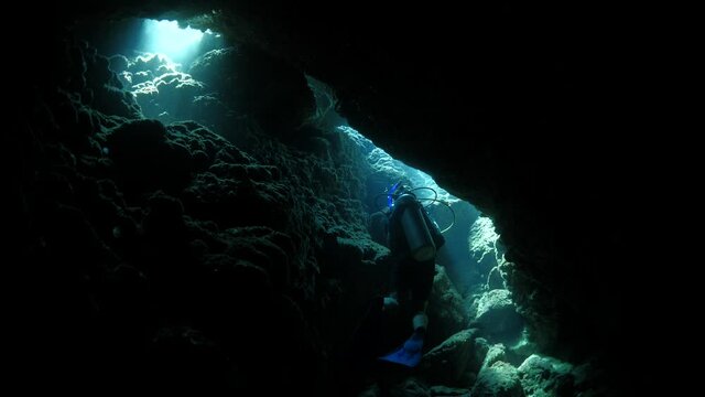 cave diving underwater scuba divers exploring caves ocean scenery sun beams and rays background