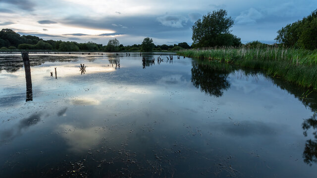 View over Arcot Pond, Cramlington, Northumberland, England, UK. In blue evening light with clouds overhead.