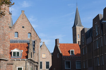 Naklejka premium Medieval brick facades with typical Dutch orange roof tiles against a blue sky on a sunny day