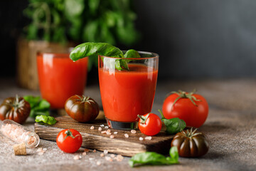 Tomato juice and fresh tomato with basil on rustic background