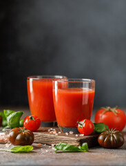 Tomato juice and fresh tomato with basil on rustic background