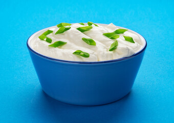 Bowl of sour cream on blue background