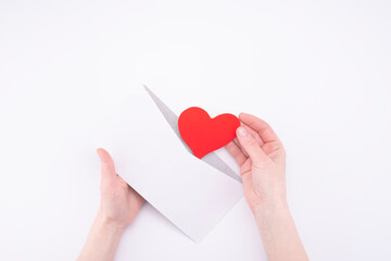 hands take out heart Valentine from white envelope on white background. declaration of love concept