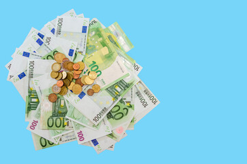 A pile of 100 Euro banknotes and coins isolated on a blue background. Copy of space. place for text. Business concept.View from above.