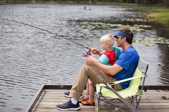 Father And Son Fishing On Dock At Moose Creek Reservoir In Northern Idaho, USA