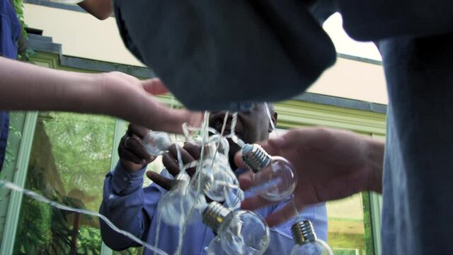 CU LA Men and boy (14-15) untangling string lights / Dinton, Wiltshire, United Kingdom