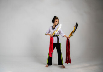 beautiful girl in white does kung fu training poses with fighting swords