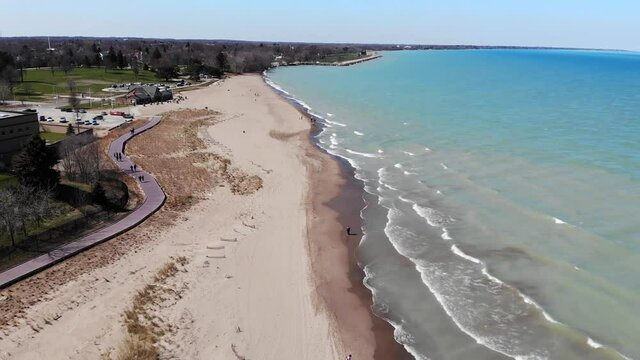 People strolling over the weekend on the waterfront of Lake Michigan in Illinois. View from the drone to the beach and the embankment of the Great Lake.