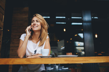  happy hipster girl making photo with cell telephone for a chat with friends while sitting in cafe