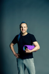 Portrait of a young man with an unusual hairstyle of mohawk from blue braids in sportswear keeps...
