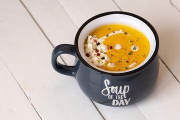 Pumpkin soup in a blue bowl isolated. Inscription: soup of the day. Vegetarian lunch or dinner. Healthy food concept. Copy space. 