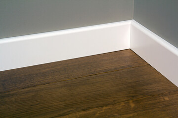 Close up of white plastic plinths on dark wooden oak floor parquet.