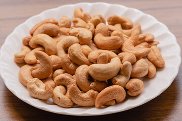 Tasty cashew nuts on the wood table background with natural light, A food that is beneficial to health Eaten as a snack is tasty and contains vitamins K, E, B6, Phosphorus, Magnesium and antioxidants.