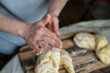 Step by step process of making yeast bread. Woman clearing hands from flour above wooden board with dough.