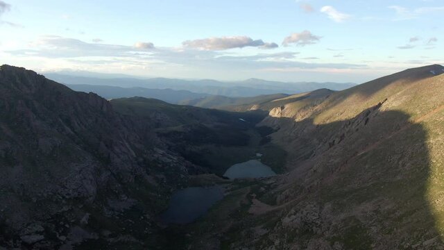 Aerial shot of lake in valley amidst mountains against sky, drone flying over natural landscape - Mount Evans, Colorado