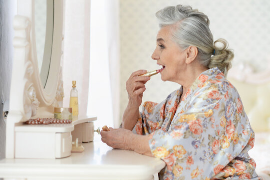 Portrait of happy senior woman applying makeup