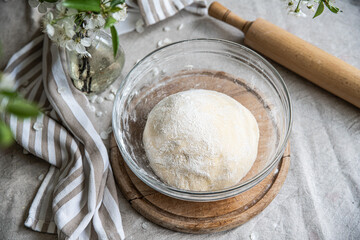 Step by step process of making yeast bread. Yeast dough rising in glass bowl on table.