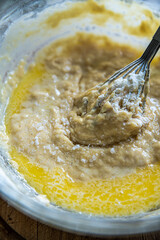 Step by step process of making yeast bread. Mixing butter in batter with a whisk.