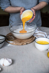 Step by step process of making yeast bread.  Adding egg yolks into bowl with yeast starter.