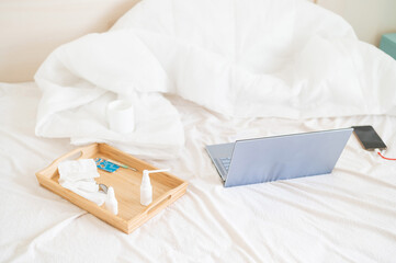 On the patient bed is a laptop and a wooden tray with medicines and pills. No people. Various cold medicines.