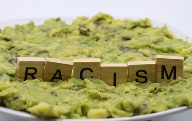 Close up of isolated word racism spelled by wooden letters on disgusting green slimy stodge (focus...