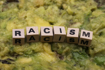 Close up of isolated word racism spelled by wooden letters on disgusting green slimy stodge (focus...