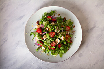 Feta cheese strawberry cucumber rocket (arugula) salad with pecan nuts - healthy vegetarian food. View from above, top view
