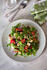 Feta cheese strawberry cucumber rocket (arugula) salad with pecan nuts - healthy vegetarian food. View from above, top view