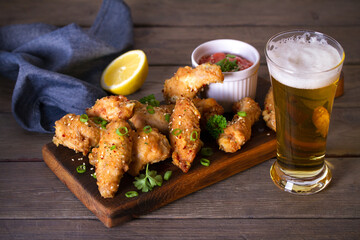 Crispy chicken wings with sauce and glass of lager beer. Horizontal image