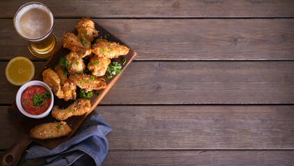 Crispy chicken wings with sauce and glass of lager beer. Overhead horizontal image. Copy space, room for text