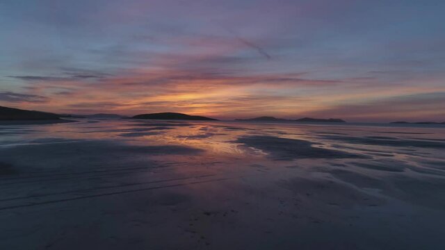 Isle of Barra, Scotland. Outer Hebrides. Scotland. Epic aerial drone video of sunset of the Isle of Barra airport with reflection in the water