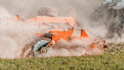 Agricultural equipment shreds the plowed land. A crawler tractor pulls a harrow to loosen the soil...