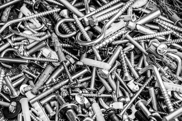 heap of metal screws, nuts and bolts. Silver filter photo. Metal fastening manufacture. Hardware for repair or fixing
