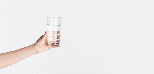 Cropped view of millennial girl holding glass of clear water on white background, empty space