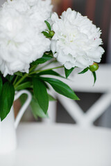 Close up a beautiful bouquet of white peonies stands on a light table