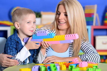 Fototapeta premium Woman and little boy playing with colorful plastic blocks together