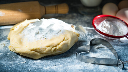 Ingredients for making cookies: dough, egg and flour on blue table