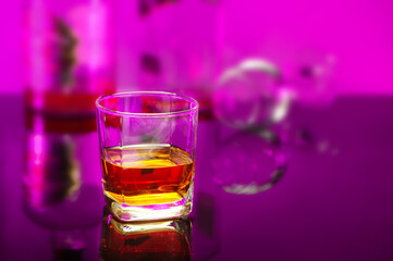 still life whiskey glass with the blurred bottle backdrop on the red ambient background
