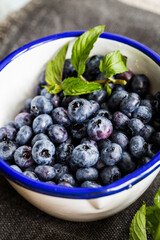 Fresh blueberries and mint leaves  in white and blue metal ladle.