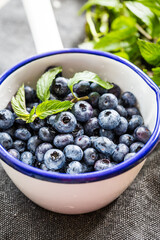 Fresh blueberries and mint leaves  in white and blue metal ladle.