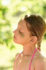 
Portrait of a beautiful girl with a snail. A snail on the face of a child. A young girl is playing with a snail. Summer walks in the park.