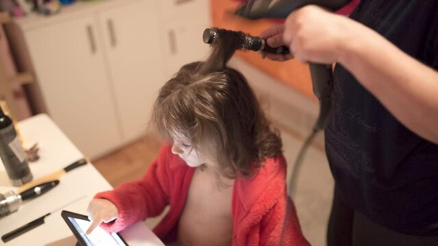 Single mother drying hair to her adorable daughter in bathrobe