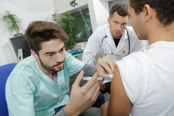 junior doctor being supervised administering injection