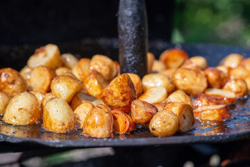 Grilled potato on frying pan on open fire