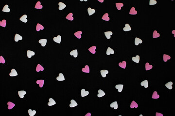 White and pink little sugar hearts pattern on dark background. Birthday party and Valentine's Day concept