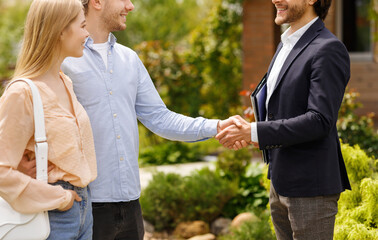 Cropped view of real estate broker shaking hands with his clients, closing house rental deal outdoors