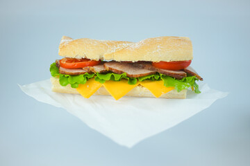 Big tasty sandwich with tomato lettuce with soap and ham on a white plate