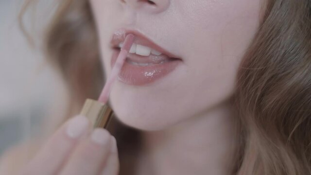 Close up of woman's lips while she's putting on lip gloss